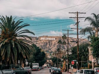 auro su viale di Los Angeles con palme sui due lati, da cui si scorge la scritta Holliwood